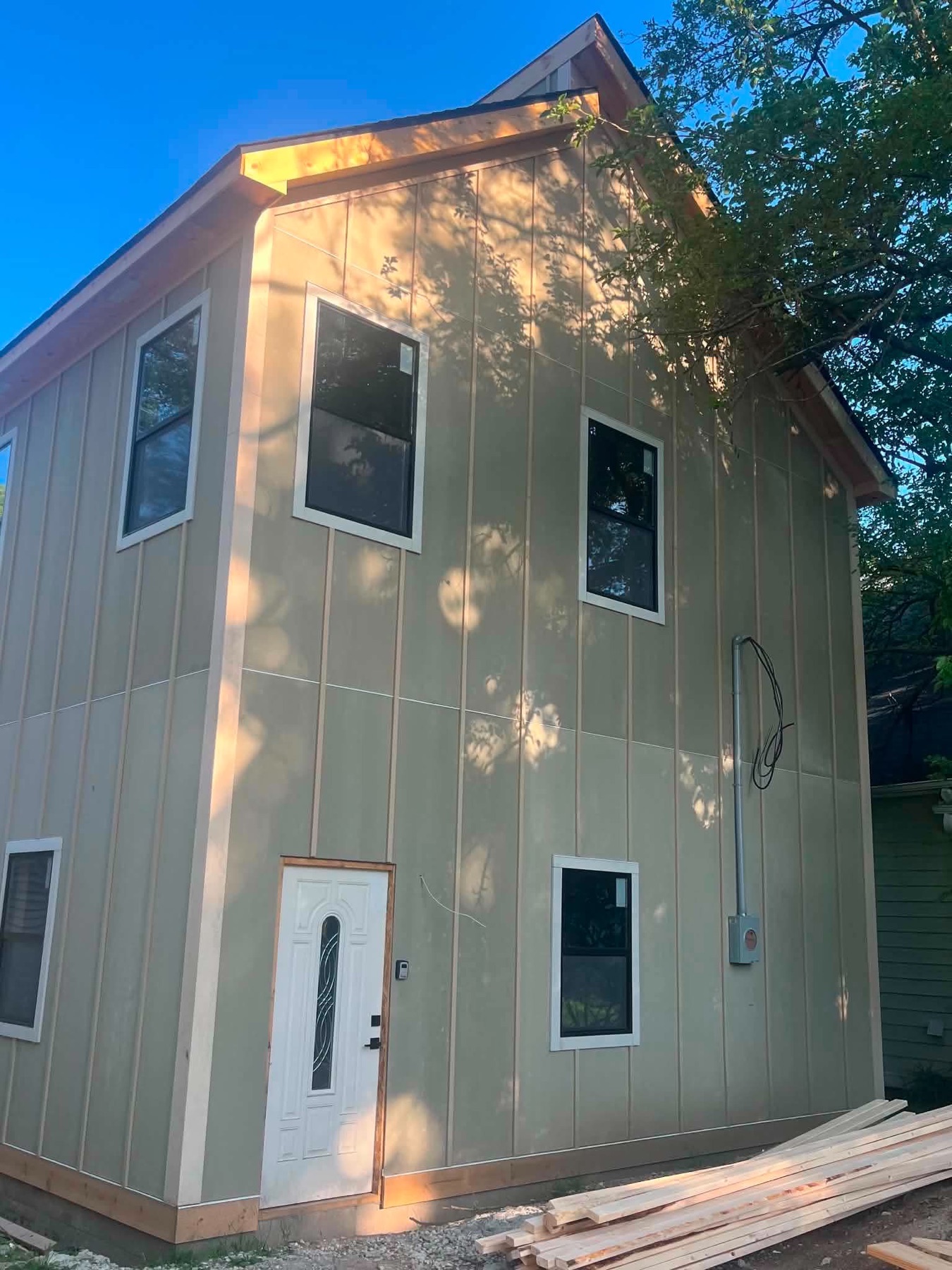 Newly built two-story home with finished gray siding and white front door